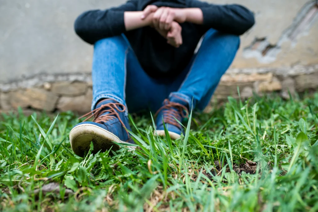 Young boy sitting in the grass.