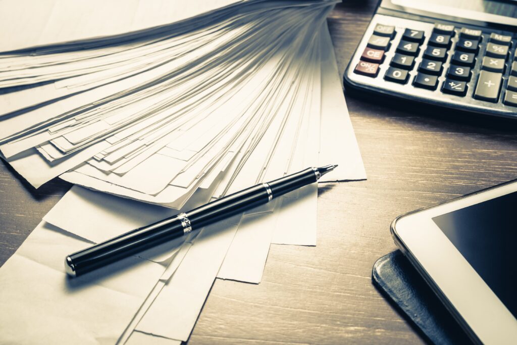 Documents, a fountain pen and a calculator on a desk.