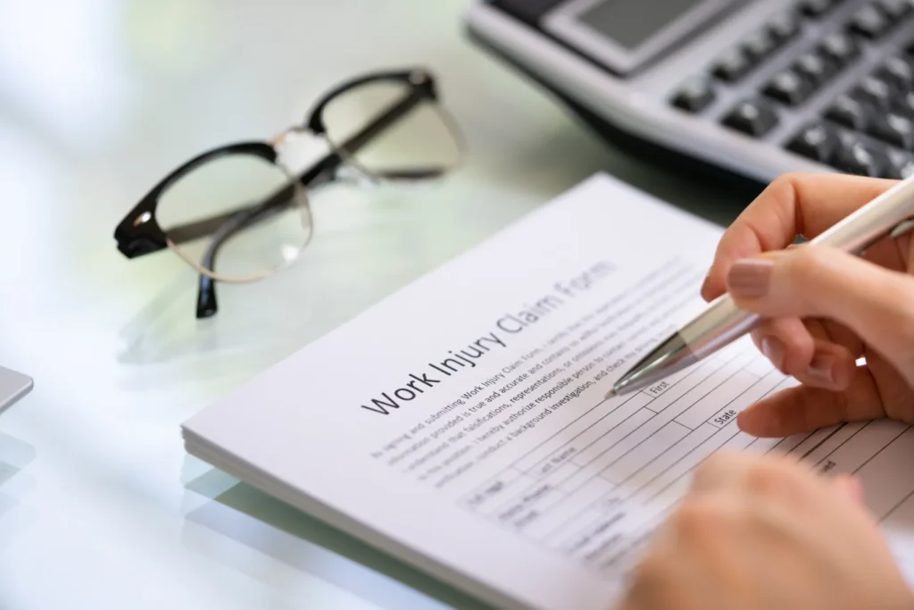 A workplace injury form and a pair of eyeglasses on a desk.