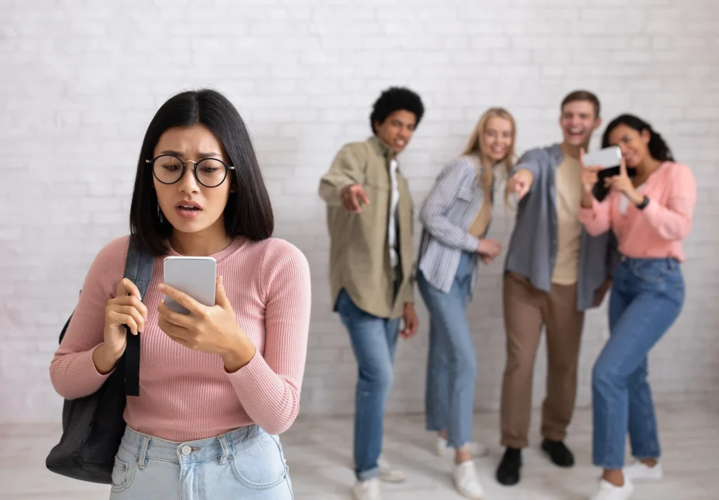 Young female holding phone and group of people pointing at her.