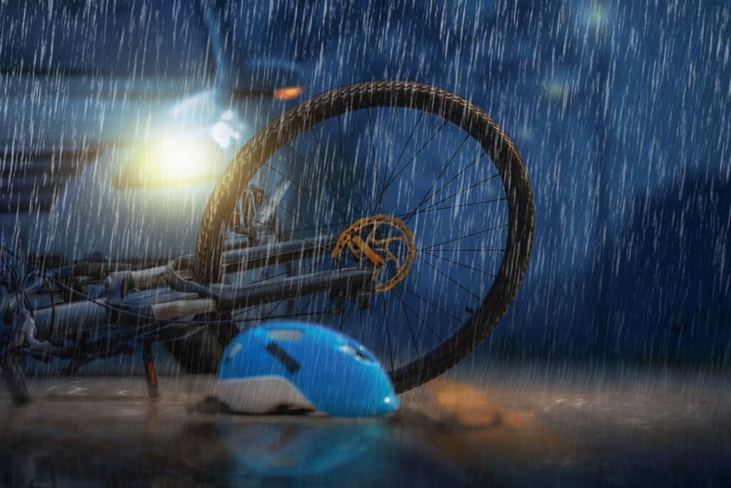 A bicycle in front of a car in the rain. 