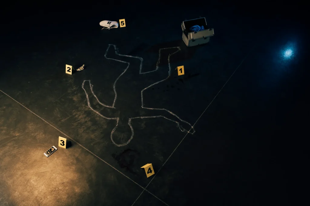 Crime scene with chalk outline of body, evidence markers, and various items including a shoe, phone, and toolbox – related to a murder or manslaughter investigation.